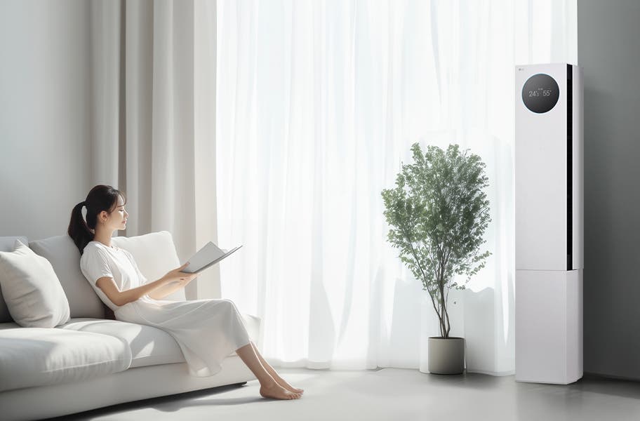 LG 휘센 AI 오브제컬렉션 뷰I 프로 에어컨이 오른쪽에 세워져 있으며, 원형 디스플레이에는 24.5°C와 55%라는 숫자가 표시되어 있습니다. 에어컨 왼쪽에는 커다란 창문이 있고, 창문을 통해 밝은 자연광이 들어오고 있습니다. 창문 앞에는 화분에 심어진 녹색 식물이 놓여 있습니다. 왼쪽에는 흰색 소파에 앉아 책을 읽고 있는 여성이 보입니다. 그녀는 흰색 원피스를 입고 있으며, 소파에는 흰색 쿠션이 놓여 있습니다.