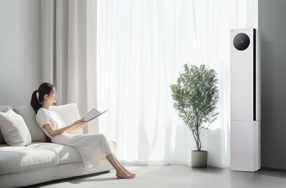 LG 휘센 AI 오브제컬렉션 뷰I 프로 에어컨이 오른쪽에 세워져 있으며, 원형 디스플레이에는 24.5°C라는 숫자가 표시되어 있습니다. 에어컨 왼쪽에는 커다란 창문이 있고, 창문을 통해 밝은 자연광이 들어오고 있습니다. 창문 앞에는 화분에 심어진 녹색 식물이 놓여 있습니다. 왼쪽에는 흰색 소파에 앉아 책을 읽고 있는 여성이 보입니다. 그녀는 흰색 원피스를 입고 있으며, 소파에는 흰색 쿠션이 놓여 있습니다.