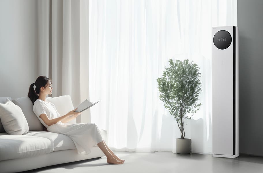 LG 휘센 AI 오브제컬렉션 타워I 에어컨이 오른쪽에 세워져 있으며, 원형 디스플레이에는 24.5°C와 55%라는 숫자가 표시되어 있습니다. 에어컨 왼쪽에는 커다란 창문이 있고, 창문을 통해 밝은 자연광이 들어오고 있습니다. 창문 앞에는 화분에 심어진 녹색 식물이 놓여 있습니다. 왼쪽에는 흰색 소파에 앉아 책을 읽고 있는 여성이 보입니다. 그녀는 흰색 원피스를 입고 있으며, 소파에는 흰색 쿠션이 놓여 있습니다.