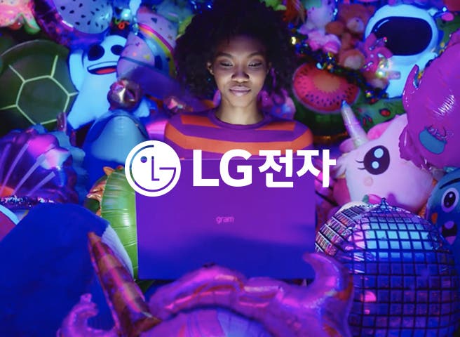 gram 노트북을 들고 있는 사람이 보이며, 주변에는 유니콘, 거북이, 귀여운 얼굴 모양의 풍선들이 가득 차 있습니다. 흰색 LG로고와 흰색 글씨로 LG전자라는 텍스트가 적혀 있습니다.