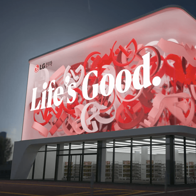 외벽에 사이니지가 설치된 건물이 보입니다. 사이니지의 왼쪽 상단에는 LG전자 로고가 보이며 Life's Good.이라는 문구가 쓰여 있습니다. 주변에는 나무와 가로등이 있습니다. 밤 시간대의 분위기가 느껴지는 이미지입니다.