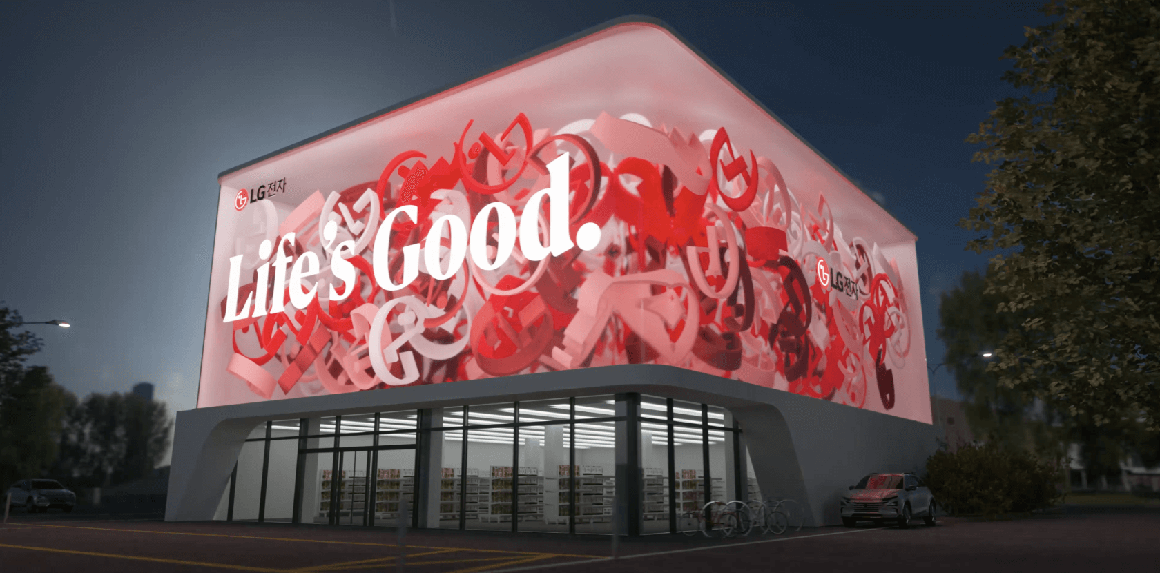 외벽에 사이니지가 설치된 건물이 보입니다. 사이니지의 왼쪽 상단에는 LG전자 로고가 보이며 Life's Good.이라는 문구가 쓰여 있습니다. 주변에는 나무와 가로등이 있습니다. 밤 시간대의 분위기가 느껴지는 이미지입니다.