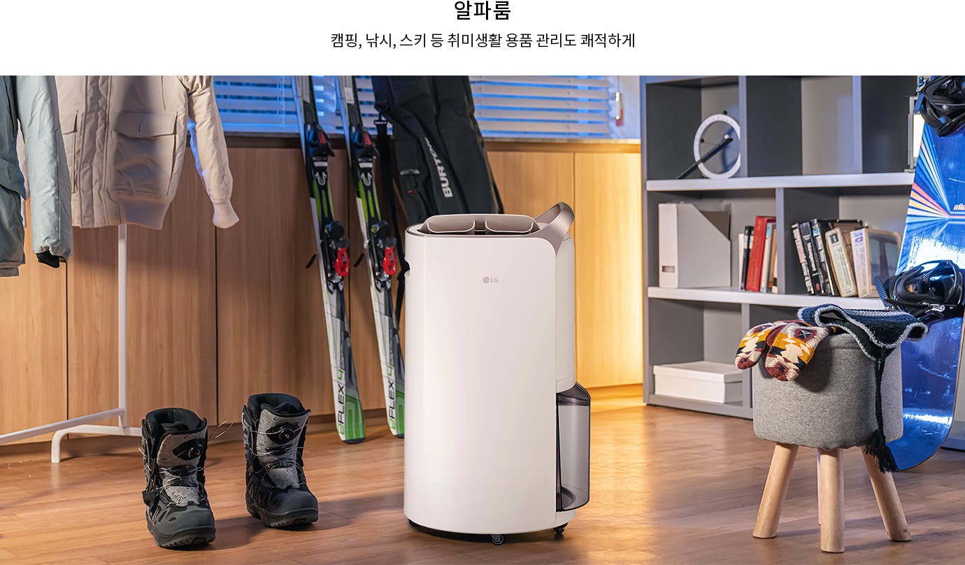 알파룸이라는 제목 아래 캠핑, 낚시, 스키 등 취미생활 용품 관리도 쾌적하게라는 문구가 있습니다. 실내 공간에 옷걸이에 걸린 재킷과 바닥에 놓인 부츠, 스키 장비가 보입니다. LG 로고가 있는 가전 제품이 놓여 있으며, 책장에는 여러 권의 책과 장식품이 진열되어 있습니다. 스노보드와 모자, 장갑이 있는 의자가 있습니다.