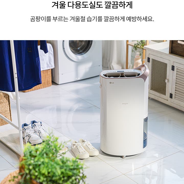 겨울 다용도실도 깔끔하게. 곰팡이를 부르는 겨울철 습기를 깔끔하게 예방하세요. 흰색 LG 휘센 제습기가 바닥에 놓여 있으며, 주변에는 운동화와 빨래 건조대가 있습니다. 배경에는 세탁기와 수납장이 보입니다. 밝은 타일 바닥과 식물이 함께 어우러져 깔끔한 분위기를 연출합니다.