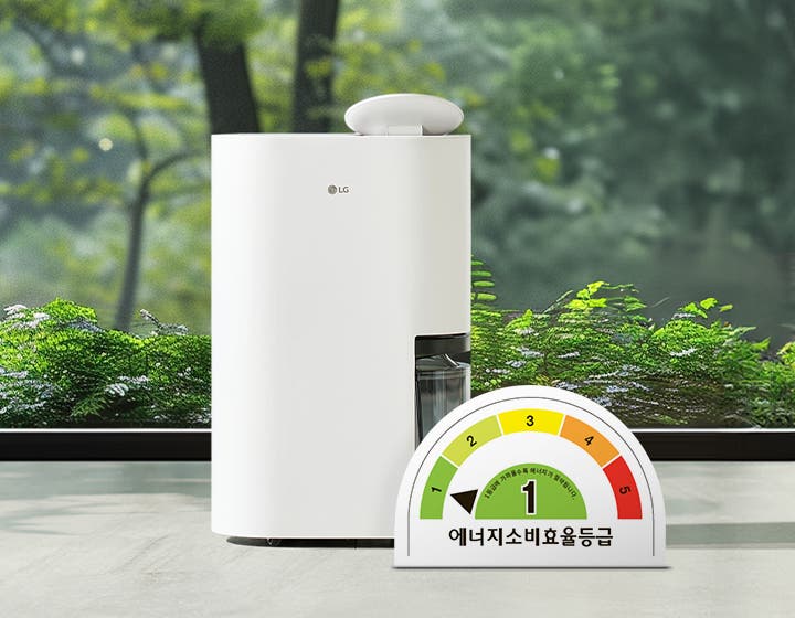 LG 휘센 오브제컬렉션 제습기가 실내에 놓여 있으며, 제품은 매끄러운 흰색 외관을 가지고 있습니다. 제습기 옆에는 투명한 물통이 보입니다. 이미지 하단에는 에너지 소비 효율 등급을 나타내는 반원형 그래프가 있으며, 에너지소비효율등급이라는 문구와 함께 1등급이 표시되어 있습니다. 배경에는 큰 창문을 통해 녹색 식물이 보입니다.
