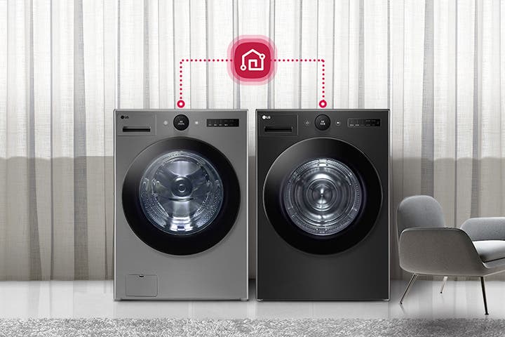 세련된 실내 공간에 두 대의 LG 세탁기가 나란히 놓여 있으며, 그 위에는 스마트홈 연결을 상징하는 아이콘이 점선으로 연결되어 있습니다. 배경은 커튼으로 장식되어 있으며, 세탁기 옆에는 의자와 테이블이 배치되어 있습니다.