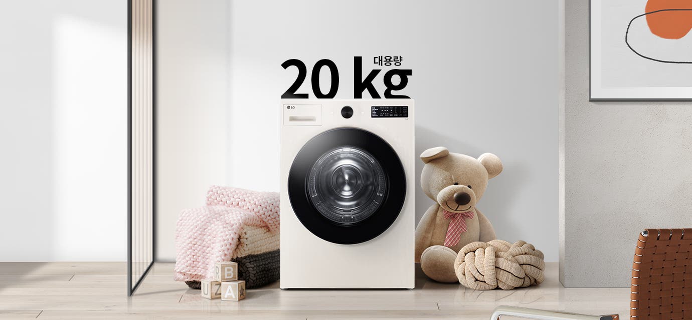 세탁기가 놓여 있으며, 20kg 대용량이라는 텍스트가 있습니다. 세탁기 주변에는 분홍색 담요와 곰 인형이 있고, 바닥에는 알파벳 블록이 놓여 있습니다. 배경은 밝은 색상의 벽과 그림이 걸려 있습니다.