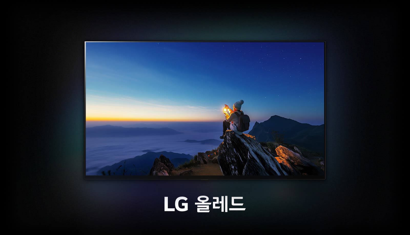 LG 올레드(OLED) TV 화면이 있습니다. TV 화면 속에는 어둠이 짙게 깔린 푸른 새벽 하늘 아래, 산 정상으로 보이는 바위 위에 한 사람이 앉아있는 풍경이 보입니다. 이 사람은 등산복을 입고 배낭을 메고 있으며, 두 손으로 밝게 빛나는 작은 랜턴을 감싸 쥐고 있습니다.  화면 아래에는 'LG 올레드'라는 흰색 텍스트가 중앙에 배치되어 있습니다.