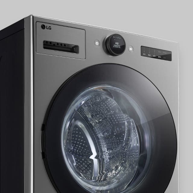 LG 로고가 있는 세련된 디자인의 세탁기입니다. 원형의 투명한 문이 있으며, 디지털 디스플레이와 조작 버튼이 있습니다. 금속성의 외관이 현대적이고 깔끔한 느낌을 줍니다.