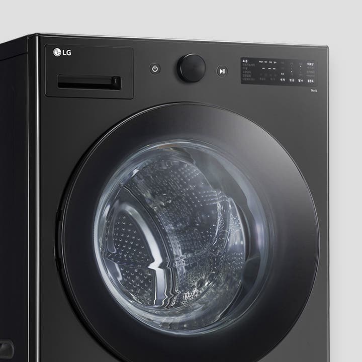 검은색 LG 세탁기가 보입니다. 세탁기 전면에 투명한 문이 있으며, 내부 드럼이 보입니다. 상단에는 전원 버튼과 조작 다이얼이 있고, 디지털 디스플레이 화면이 있습니다. 디스플레이에는 다양한 세탁 옵션이 표시되어 있습니다.