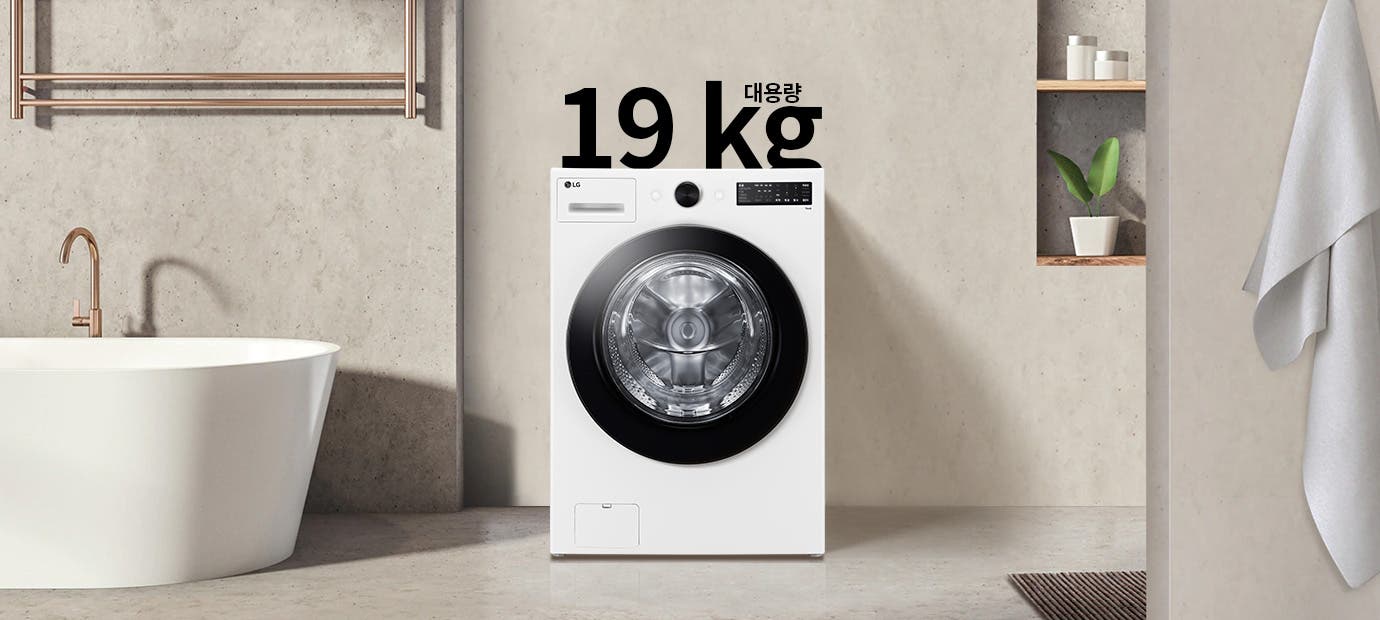 세탁기가 욕실에 놓여 있으며, 세탁기 위에는 19 kg 대용량이라는 텍스트가 있습니다. 세탁기 옆에는 욕조와 수건이 걸려 있고, 벽 선반에는 화분과 용기가 놓여 있습니다.