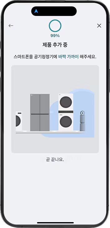 스마트폰 화면에 99%라는 숫자가 원형 그래프와 함께 상단에 표시되어 있으며, 그 아래에는 제품 추가 중이라는 문구가 있습니다. 이어서 스마트폰을 공기청정기에 바짝 가까이 해주세요.라는 안내 문구가 보입니다. 중앙에는 회색 배경 위에 다양한 가전제품이 나란히 배치되어 있으며, 왼쪽부터 냉장고, 세탁기, 건조기, 공기청정기가 순서대로 놓여 있습니다. 화면 하단에는 곧 끝나요.라는 문구가 표시되어 있습니다.