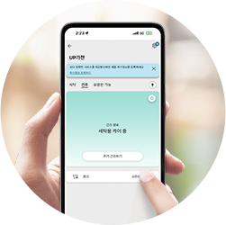스마트폰 화면에 LG UP가전 애플리케이션이 실행되어 있습니다. 세탁물 케어 중이라는 텍스트가 표시되어 있습니다. 손가락이 화면을 터치하고 있는 모습이 함께 보입니다.