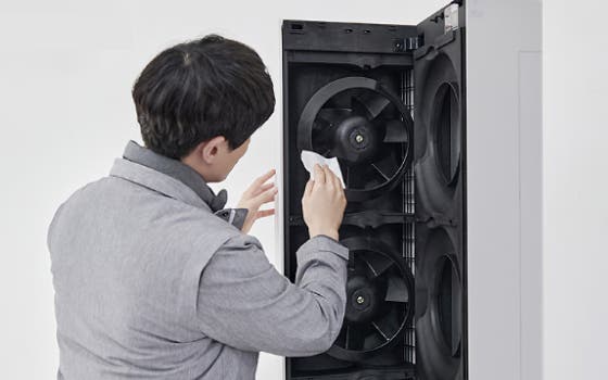 벽에 설치된 LG 벽걸이형 에어컨의 하단을 한 사람이 양손으로 열고 있는 모습입니다.