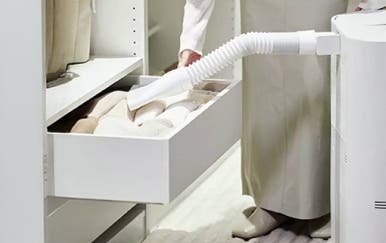 옷장 서랍 안에는 흰색 흡입구가 보이는 집중 건조 키트가 있으며, 흰색 주름관이 흰색 장치와 연결되어 있습니다.