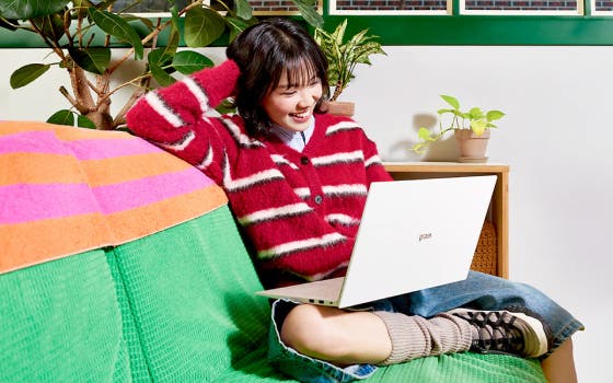 야외에서 두 명의 젊은 외국인이 흰색 gram 노트북을 들고 화면을 보며 밝게 웃고 있습니다.