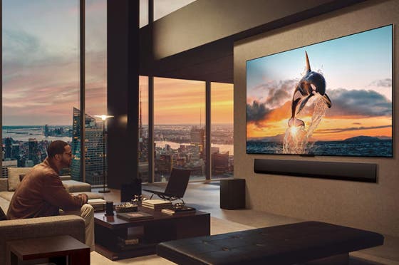 도시 풍경을 감상할 수 있는 넓은 거실. LG OLED TV는 LG 사운드바가 있는 벽에 장착되어 있습니다. TV의 원월 디자인으로 벽에 플러시 핏을 맞추고 공간과 잘 어우러집니다. 제로 커넥트 박스는 보이지만 숨겨져 있습니다.