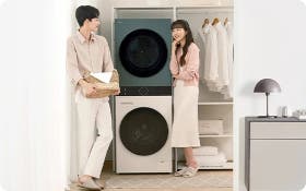 세탁기와 건조기가 세로로 설치된 공간에서 두 사람이 세탁물을 정리하는 모습