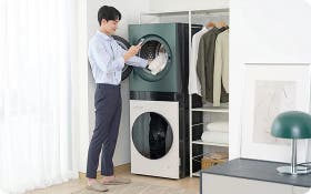 세탁기와 건조기가 세로로 설치된 공간에서 남성이 세탁물을 넣는 모습