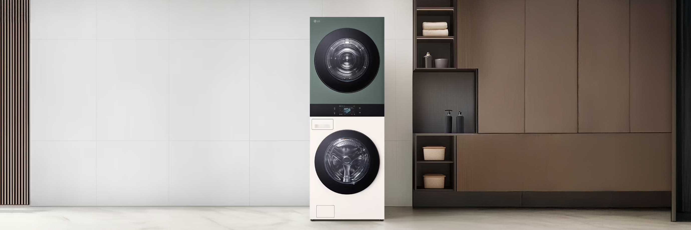 실내에 설치된 LG 워시타워로, 상단에는 녹색 건조기, 하단에는 흰색 세탁기가 세로로 구성되어 있습니다. 오른쪽에는 선반과 수납장이 있는 모듈형 선반이 배치되어 있으며, 양쪽 벽은 흰색 타일로 마감되어 있습니다.