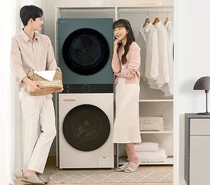 세탁기와 건조기가 세로로 설치된 공간에서 두 사람이 세탁물을 정리하는 모습