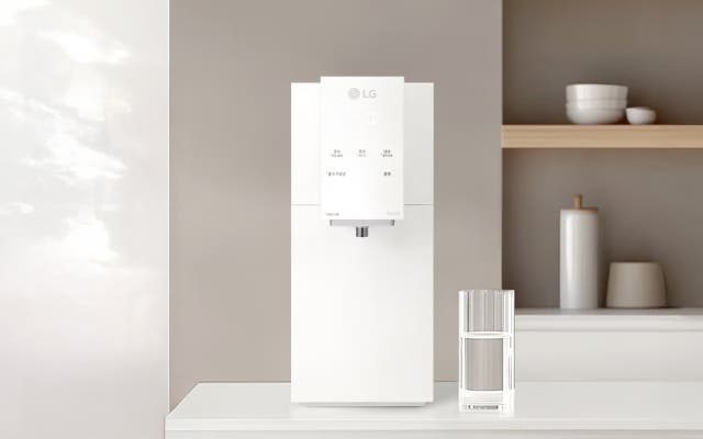 산뜻한 톤의 주방 공간에 화이트 컬러의 LG 퓨리케어 오브제컬렉션 정수기가 놓여 있어요. 옆에는 유리컵과 미니멀한 소품들이 정돈되어 배치되어, 전체적으로 깔끔하고 부드러운 분위기를 만들어 줍니다.