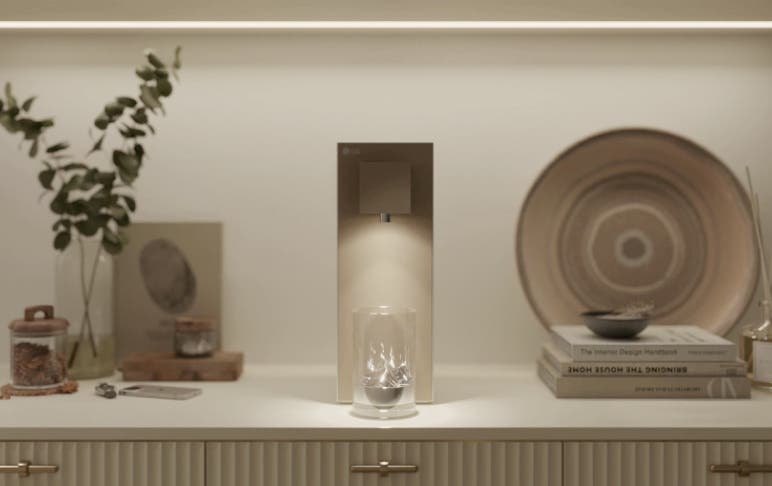 따뜻한 조명 아래 LG 퓨리케어 오브제컬렉션 데스크 정수기가 놓여 있으며, 무드 라이팅이 은은하게 비춰 주변 소품들과 함께 감각적인 분위기를 연출하고 있습니다. 잔 위로 내려오는 부드러운 조명이 공간에 포인트를 주어 아늑한 무드를 더합니다.