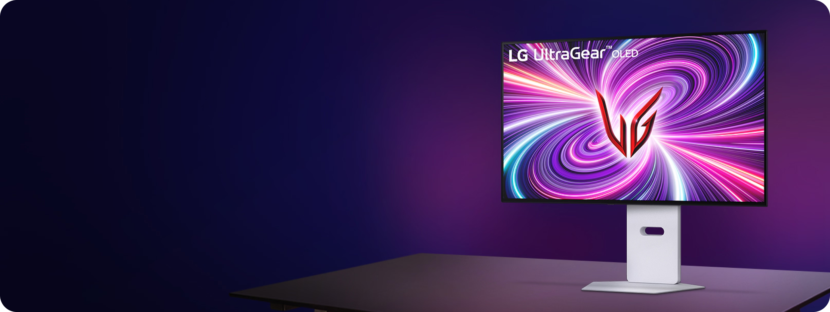 보라색 조명이 비치는 배경 앞 책상 위에 흰색 스탠드가 적용된 LG 울트라기어 OLED 모니터 1대가 놓여 있고, 화면에는 보라·분홍 계열의 소용돌이 그래픽과 붉은 로고가 표시된 모습.
