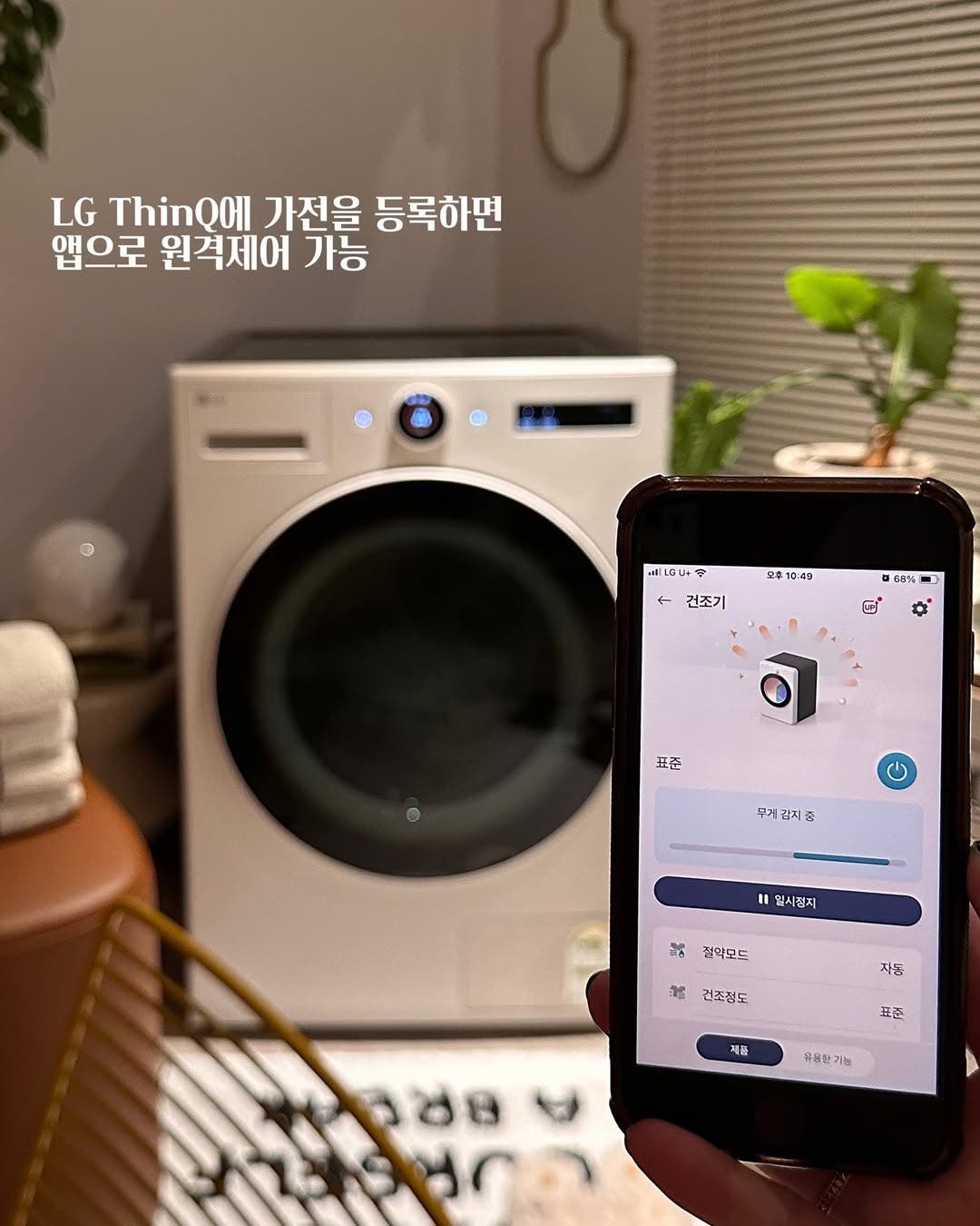 'LG ThinQ에 가전을 등록하면 앱으로 원격제어 가능'라는 글자가 포함되어 있으며, LG 트롬 오브제컬렉션 건조기가 LG ThinQ 앱을 통해 원격 제어되는 모습. 스마트폰 화면에는 건조 진행 상태와 옵션 설정이 표시되어 있음.