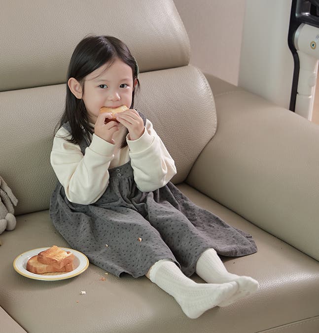 소파에 앉아 아침 식사로 토스트를 먹고 있는 어린 소녀의 모습. 옆에 LG 코드제로 A9S 오브제컬렉션이 배치되어 있음.