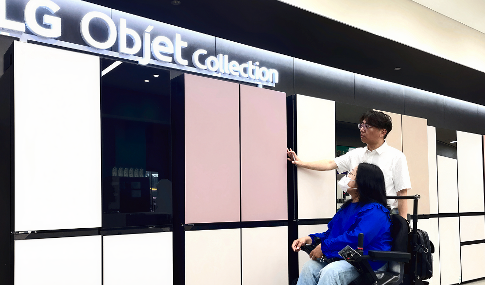 LG 매장에서 휠체어 이용 고객에게 제품을 안내하는 직원