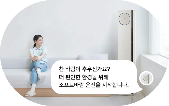 LG 에어컨 AI 음성 명령 기능 이미지입니다. 여성이 소파에 앉아 LG 스탠드형 에어컨을 바라보며 음성 명령을 하고 있으며, 명령과 응답 말풍선이 표시됩니다. 명령: '바람 안 오게 해줘' 응답: '찬 바람이 추우신가요? 더 편안한 환경을 위해 소프트바람 운전을 시작합니다.'