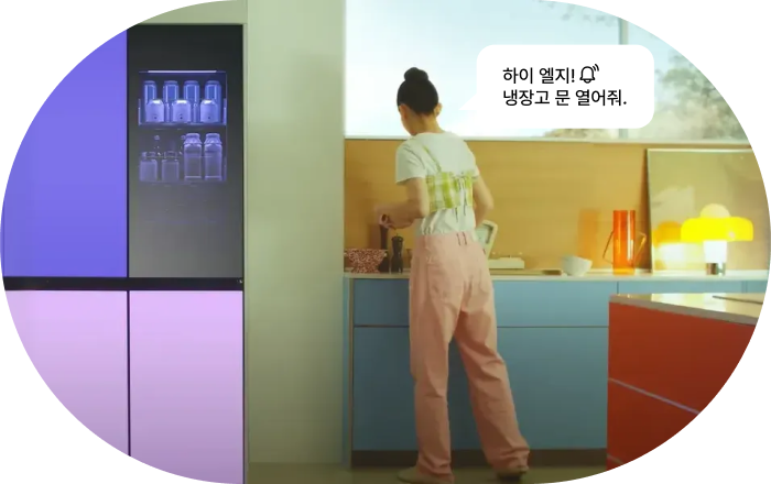 LG 냉장고 AI 음성 명령 기능 이미지입니다. 여성이 주방에서 작업하는 모습과 함께 상단 블랙, 하단 퍼플 컬러의 LG 냉장고가 보이며, 음성 명령 말풍선이 표시됩니다. 명령: '하이 엘지! 냉장고 문 열어줘.'