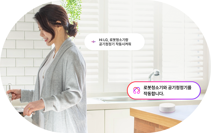 LG 스마트 스피커 AI 음성 명령 기능 이미지입니다. 여성이 주방에서 작업하는 모습과 함께 음성 명령과 응답이 말풍선으로 표시됩니다. 명령: 'Hi LG, 로봇청소기랑 공기청정기 작동시켜줘', 응답: '로봇청소기와 공기청정기를 작동합니다'