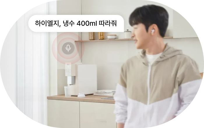 LG 정수기 AI 음성 명령 기능 이미지입니다. 남성이 주방에서 LG 정수기 쪽을 바라보며 음성 명령을 하고 있으며, 말풍선이 표시됩니다. 명령: '하이엘지, 냉수 400ml 따라줘'