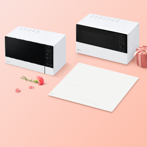 화사한 분홍색 배경 위에 화이트 컬러의 LG 광파오븐, 전자레인지, 인덕션 전기레인지 주방 가전 3종이 깔끔하게 배치된 모습. 제품 주변에 분홍색 카네이션 한 송이와 리본이 묶인 선물 상자가 놓여 있어 따뜻한 선물 시즌의 분위기를 연출함.