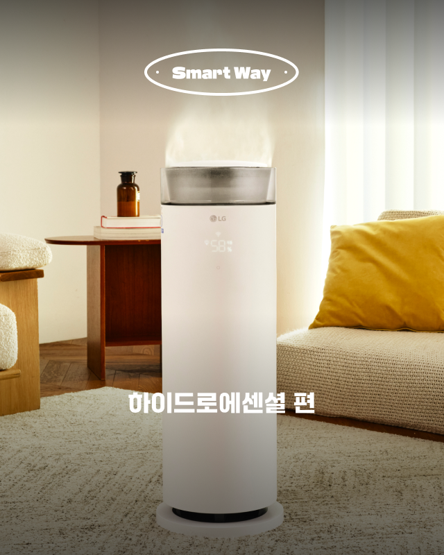 따뜻한 거실을 배경으로 수증기가 피어오르는 흰색 원통형 LG 하이드로 타워 가습기가 놓여 있음