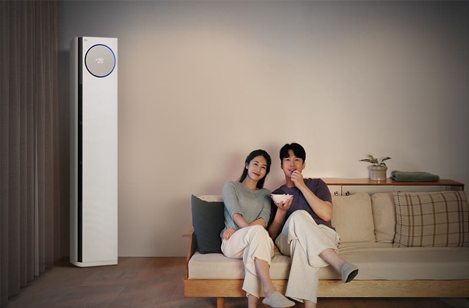 모던한 디자인의 LG 휘센 타워 에어컨이 설치된 거실에서, 푹신한 소파에 기대어 스마트폰으로 영화를 검색하는 사람. 은은한 조명 아래에서 집중하며 영화를 감상하고 있습니다.
